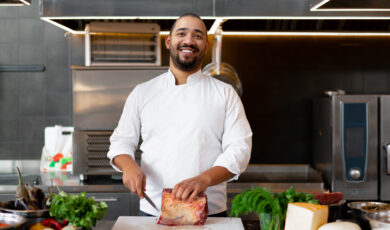 Handsome,young,african,chef,standing,in,professional,kitchen,in,restaurant